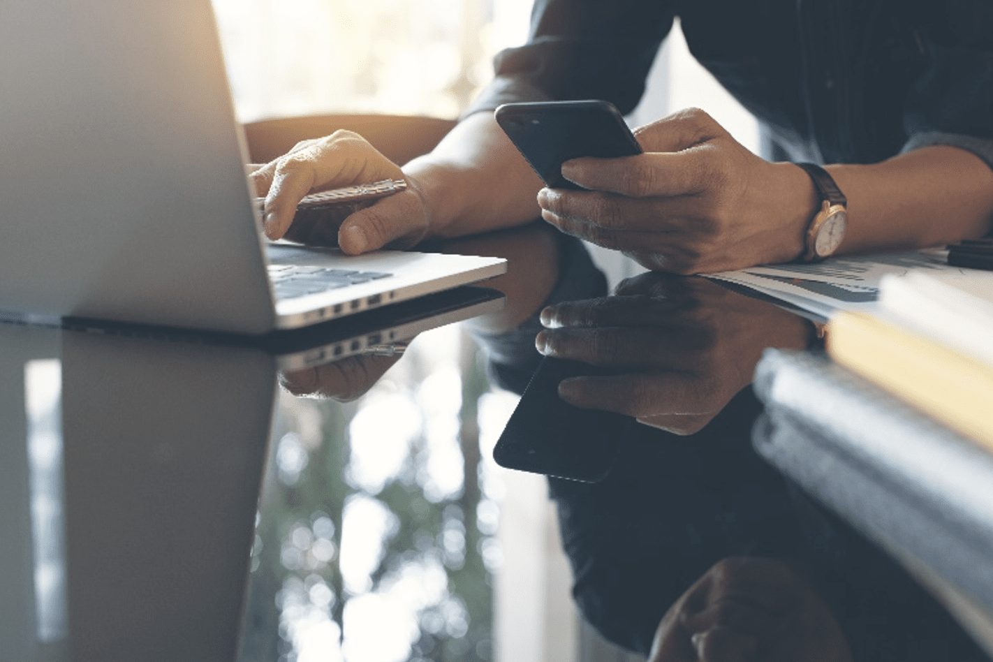 Ventes MSP - Personne tenant un smartphone à la main et travaillant sur un ordinateur portable