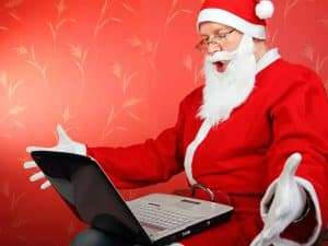 surprised santa claus get message on laptop computer. on the red background